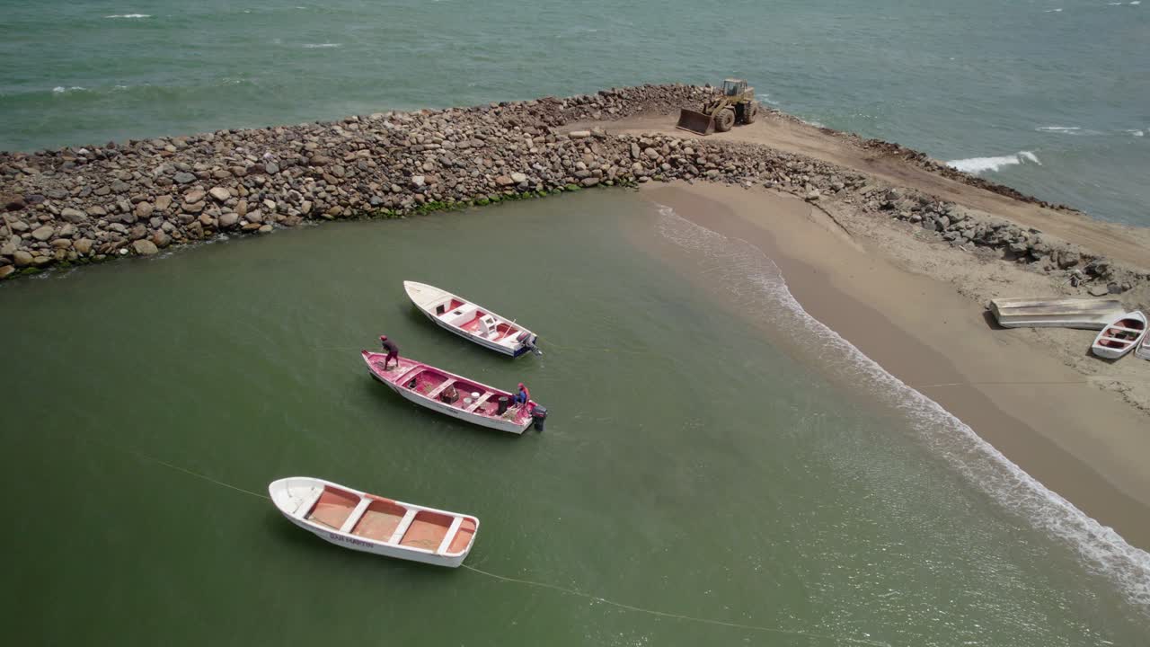 Low angle view of fishing boats leaving beach shore, with turquoise water and visible breakwaters - Venezuela