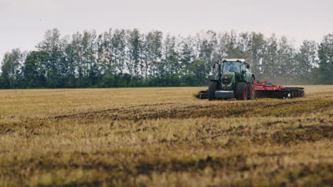 tractor plowing land on the field a flock of birds flying away