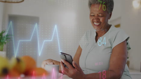 animation of cardiograph over senior biracial woman using smartphone at home