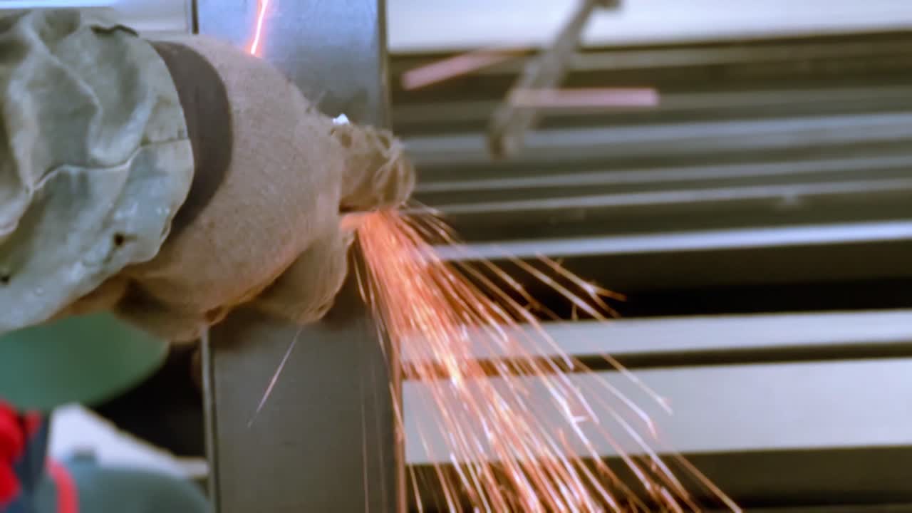 mano de hombre con guantes están sosteniendo máquina de molienda de trabajo en metal negro para suavizar la superficie