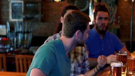 Friends-cheering-while-having-beer-at-bar-counter