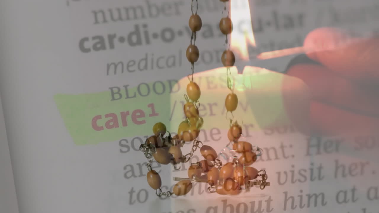 Highlighted text about care in dictionary with rosary beads and candle flame