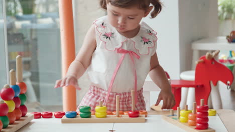 Süßes-Kleines-Mädchen-Mit-Zöpfen,-Das-Mit-Stapelspielspielzeug-Spielt,-Zahlen-Lernt-Und-Bunte-Ringe-Zählt