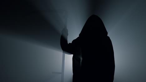 Silhouette-scytheman-frightening-indoors.-Grim-reaper-holding-scythe-in-darkness