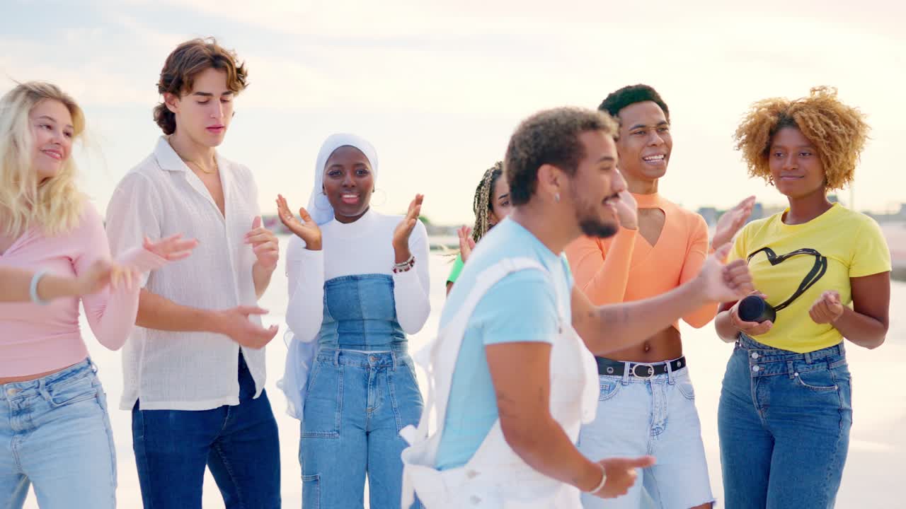 Friends encouraging a latin man dancing freestyle outdoors