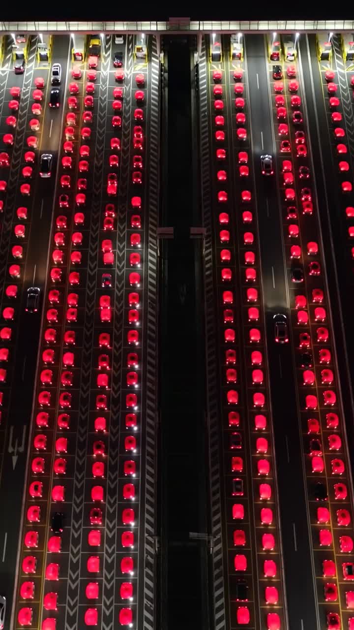 Showing dense parallel lanes of passenger vehicles moving slowly at night, with red taillights