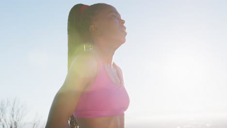 African-american-woman-exercising-outdoors-taking-rest-in-countryside-at-sunset