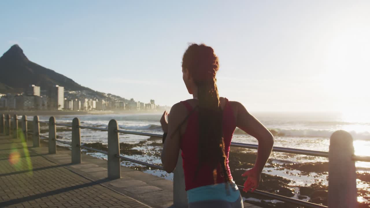 mujer afroamericana corriendo por el paseo marítimo al atardecer