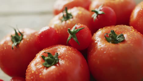 Video-of-close-up-of-fresh-tomatoes-and-cherry-tomatoes-over-wooden-background