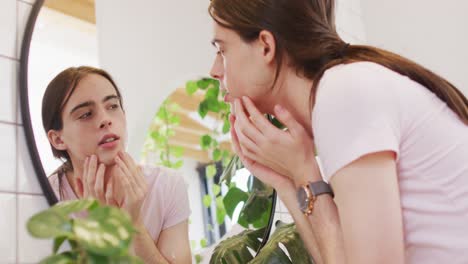 caucasian non-binary transgender woman looking in mirror