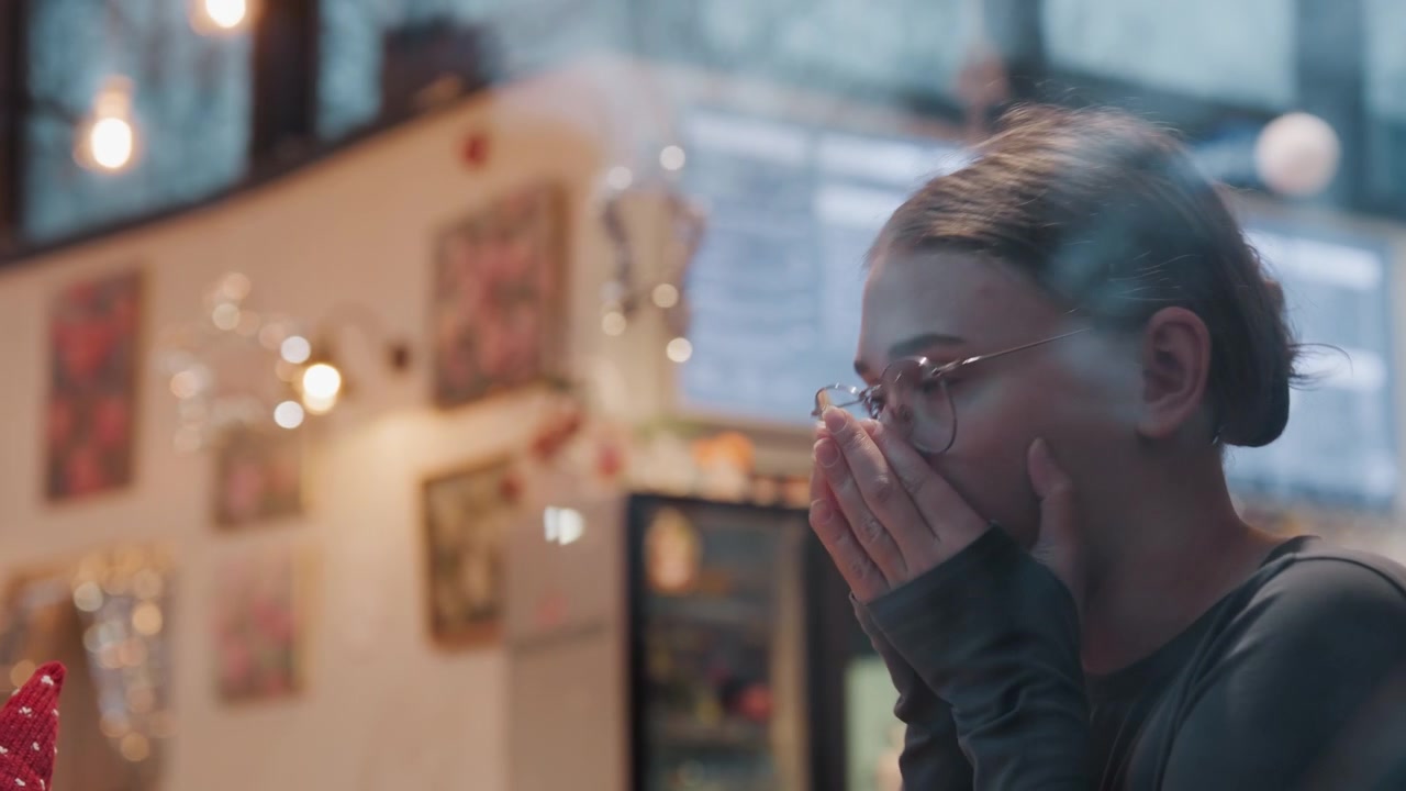 Cena contemplativa em café, mulher segurando café, olhando através da janela salpicada de chuva com vapor suave, luzes interiores quentes e quadro de menu desfocado ao fundo, momento tranquilo e reflexivo e atmosfera melancólica
