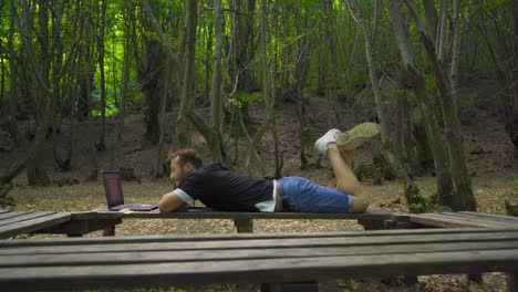 joven aventurero trabajando con una computadora portátil en la naturaleza.