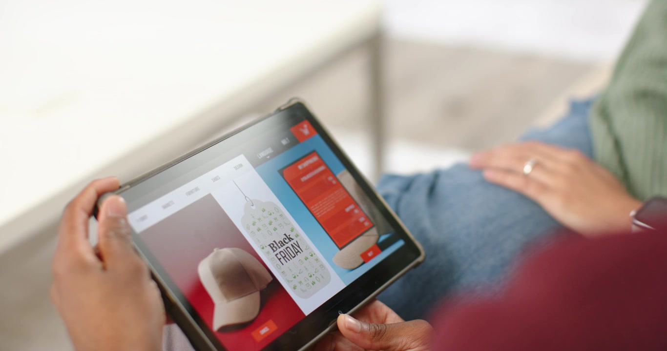 Hands are tilting and scrolling tablet on couch while viewing Black Friday deals