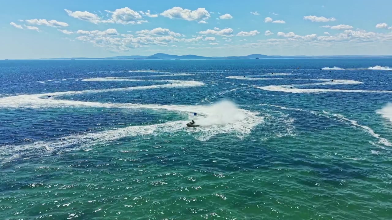 Balap Jet Ski di Air Biru Jernih di Bawah Langit Cerah Berawan, Menampilkan Beberapa Kendaraan Air Menciptakan Ombak