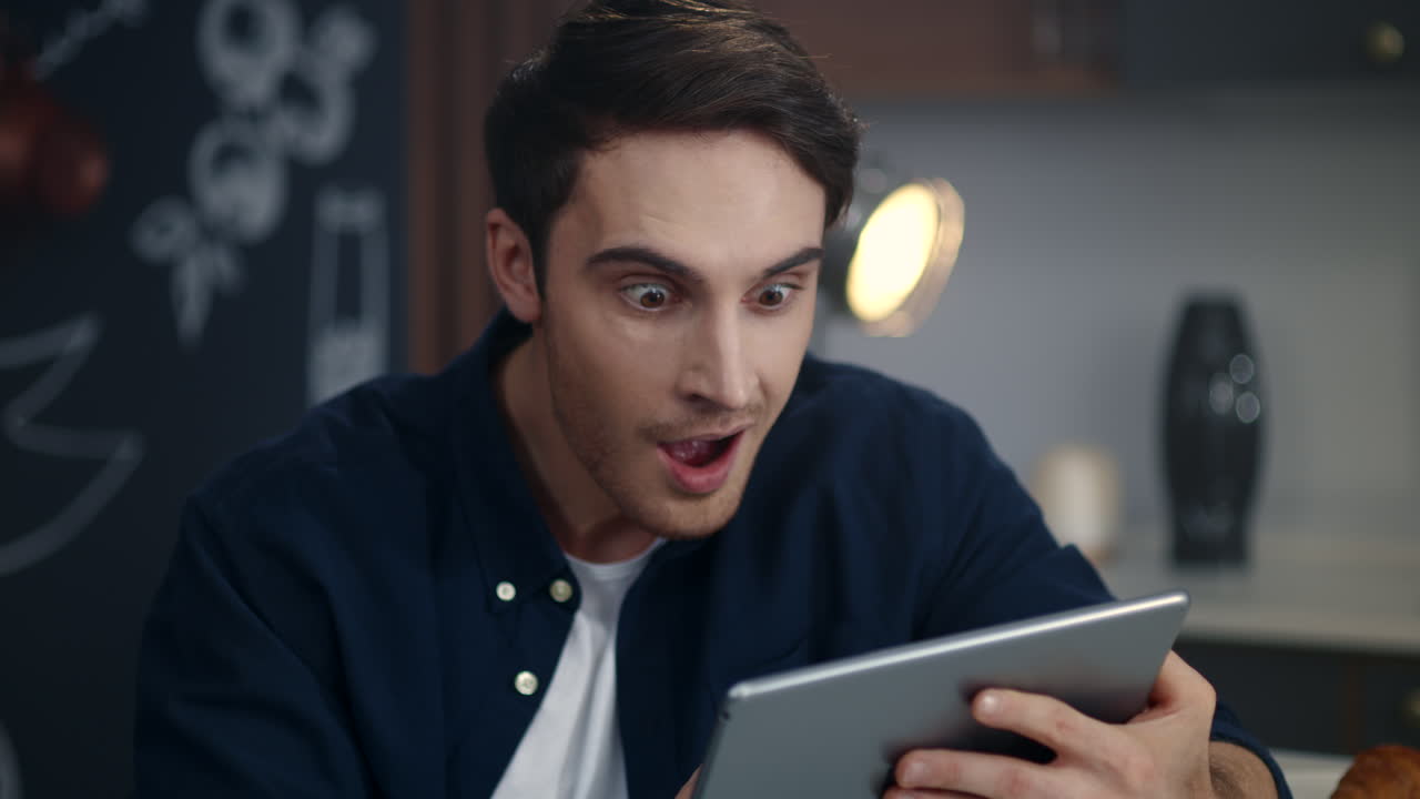 Uomo d'affari concentrato che legge i risultati del progetto sul tablet nell'ufficio di casa.