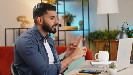 Indian-man-working-on-laptop-wearing-headset-freelance-worker-call-center-support-service-operator