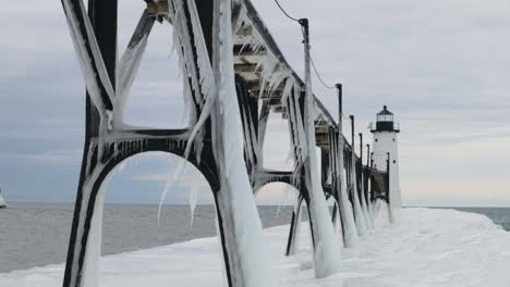 A-lighthouse-looks-over-an-icy-bridge-on-Lake-Michigan-in-Manistee,-Michigan