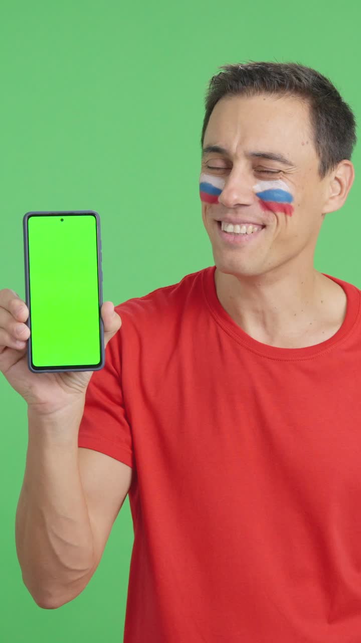 Russian supporter looking at his mobile smiling and showing it