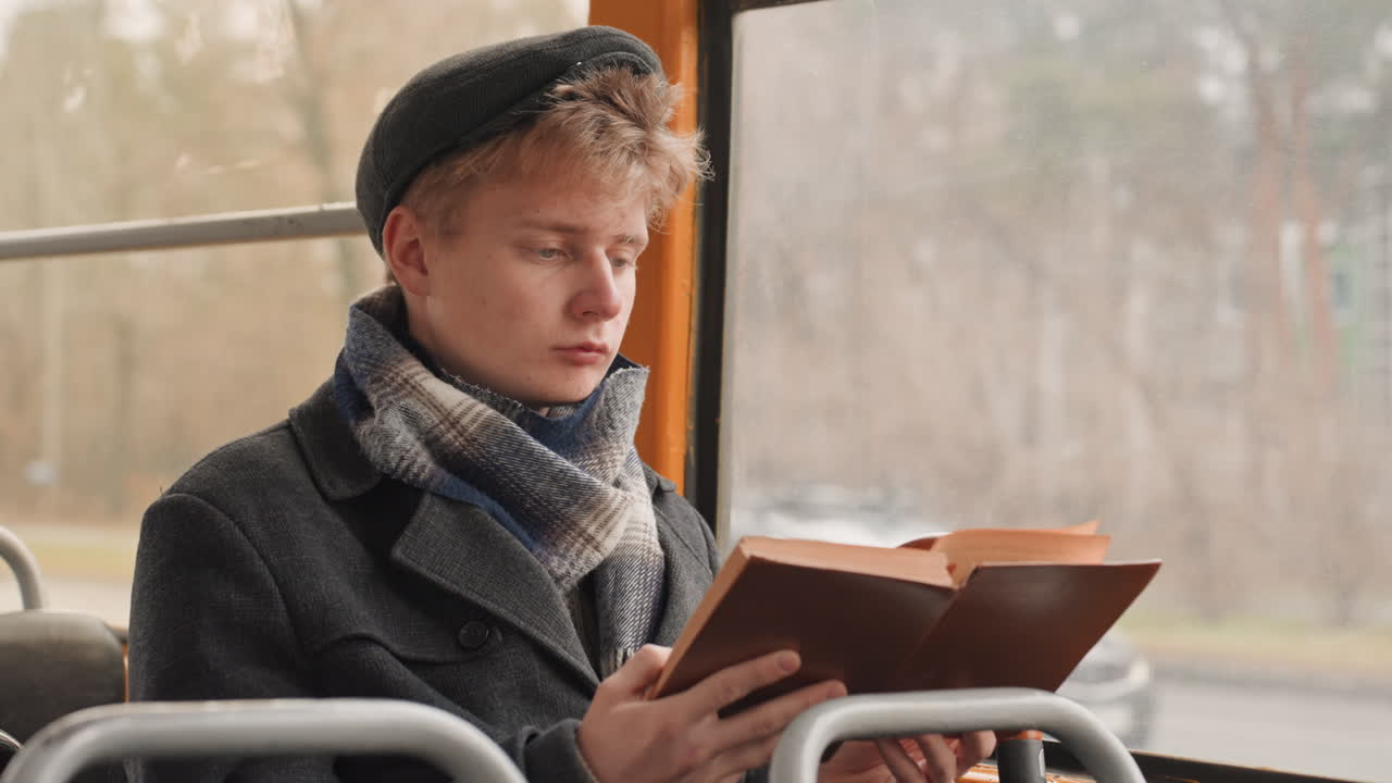 Individu créatif faisant une pause pour observer la nature et trouver l'inspiration dans un environnement calme. Écrivain prenant un moment de réflexion tranquille en regardant les arbres à travers la fenêtre d'un bus sous une douce lumière d'automne