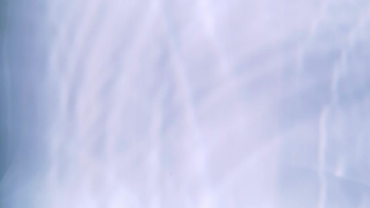 Top view slow motion of drop falling into the water surface and diverging circles on white background