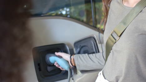 charging electric car, woman plugging in charger at home, sustainable energy