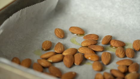 chef preparando algunas almendras frescas en una bandeja para asar con un poco de aceite de oliva
