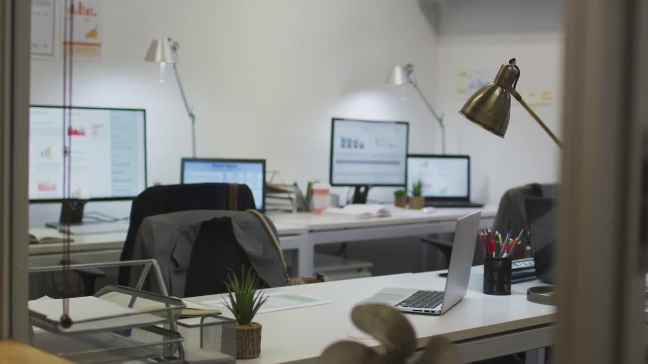 Interno di ufficio moderno vuoto con scrivanie, sedie, laptop e computer