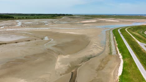 Flight-above-people-on-promenade-along-dried-out-muddy-dutch-river-bed