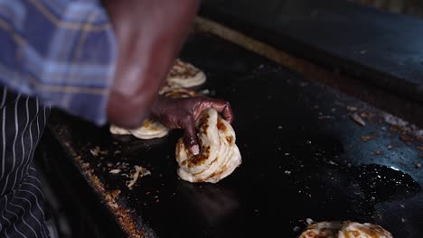 close-up of a man's hand beating the hot parotta