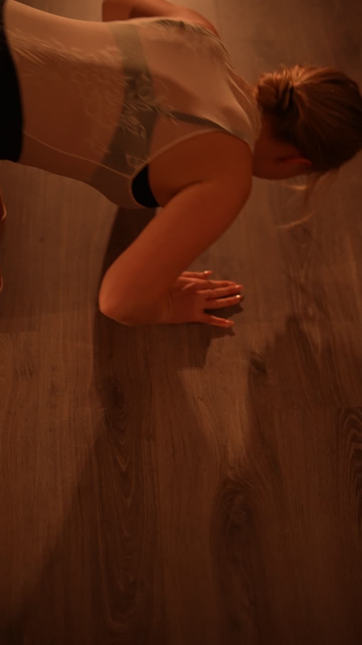 mujer realizando movimientos de baile y estiramientos en un piso de madera