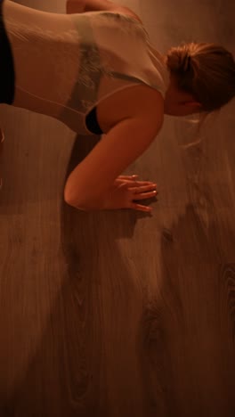 woman performing dance moves and stretches on a wooden floor