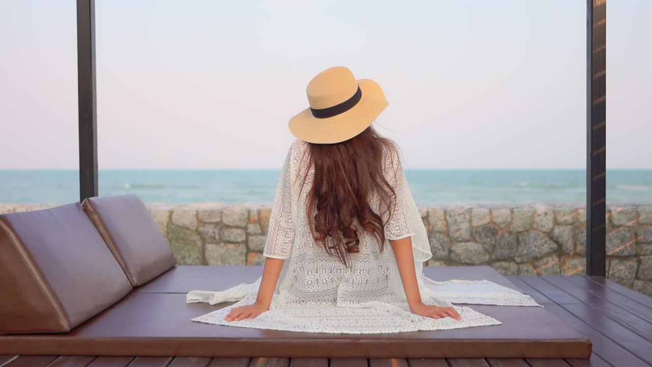 Young beautiful women sitting and relaxing on the beachside resort with a beautiful view of the endless ocean in the background