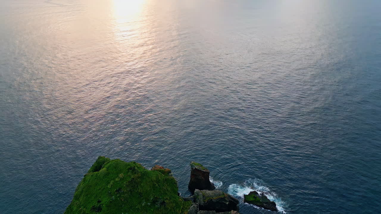 해가 지는 바다의 조용한 해변, 빛을 반사하는 물 표면의 파동.