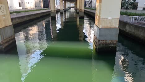 calm water flowing under a concrete bridge.