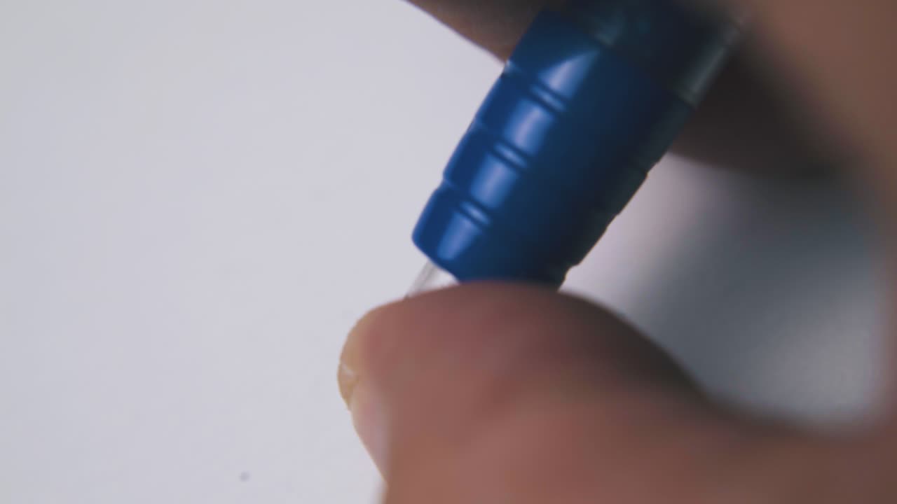 사람은  ⁇  빈 종이 위에 파란색 펜의 버튼을 누릅니다.