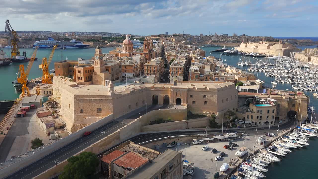Aerial views of Birgu showcase its fortified walls and the striking St. Lawrence Church rising above the city.