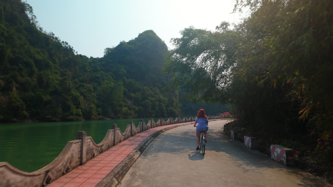 Woman Riding Bicycle In Viet Hai Village on Cat Ba Island, Vietnam. - following shot