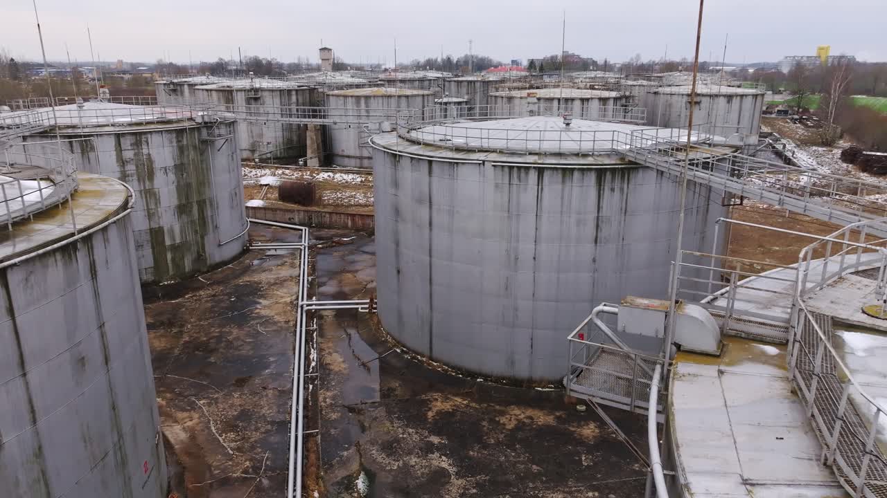 Drone flies low over damp, decaying tanks in grim weather near Saldus, Latvia