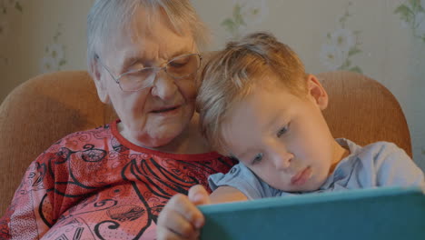 menino mostrando algo em tablet para sua avó