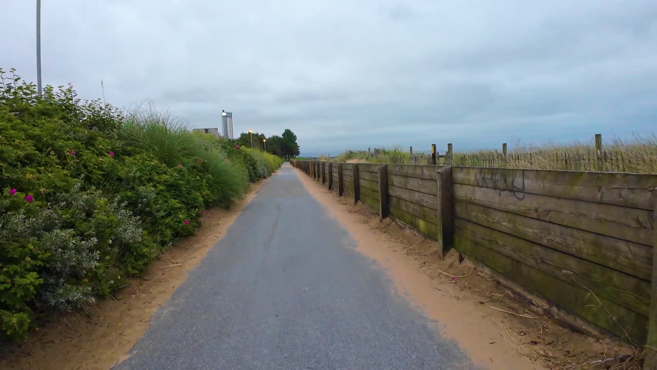 POV Smooth Moving View Moving Fast Along Tarmac Path Next to Beach. Filmed on Swansea Bay in Early Morning.