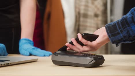 paying with smartphone in shop. buying clothes in store. showing qr code, vaccination coronavirus certificate. contactless shopping in supermarket.