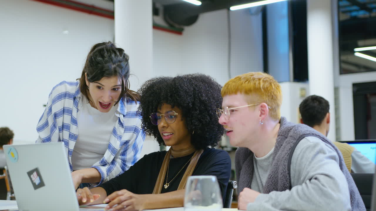 Team of Young Colleagues Collaborating and Discussing Project on Laptop in the Office