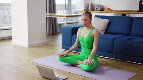 woman in sportswear talk on video call sit on yoga mat