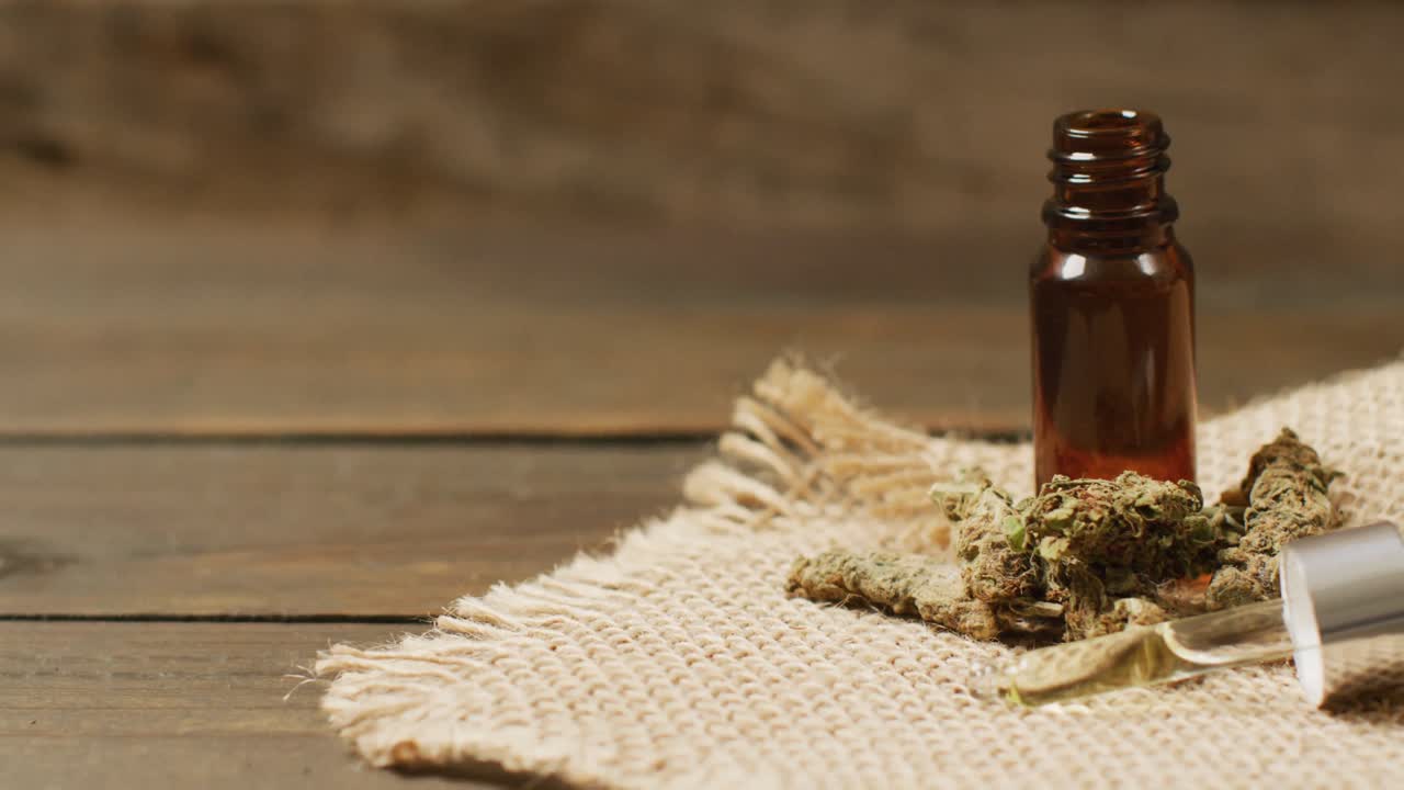 video de brotes de marihuana y una botella de extracto de cbd sobre un fondo de madera