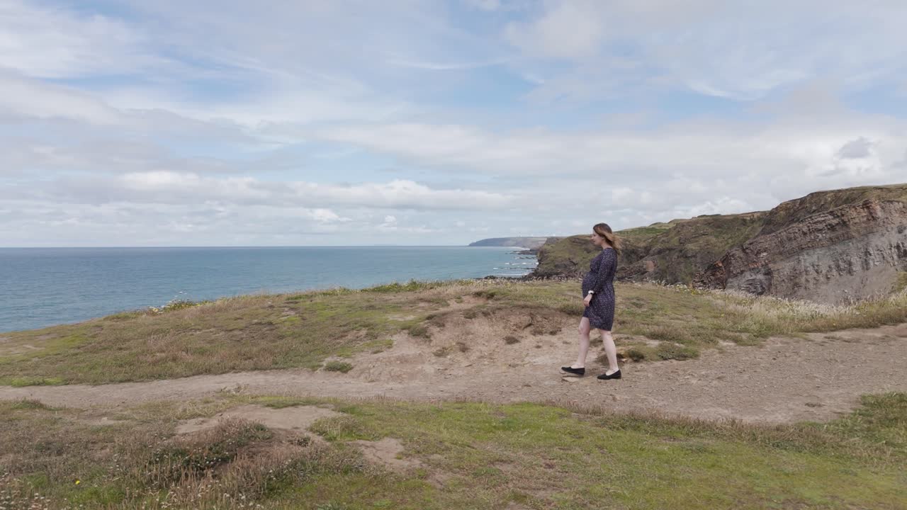 Woman walking on a coastal path overlooking the ocean