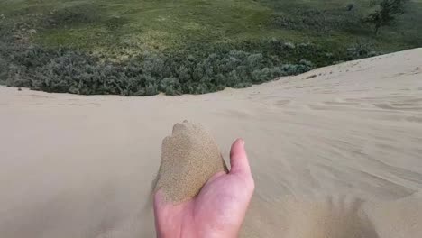 slow motion - a hand full of sand blowing away in the wind. filmed in alberta canada on a sunny day at athabasca dunes.