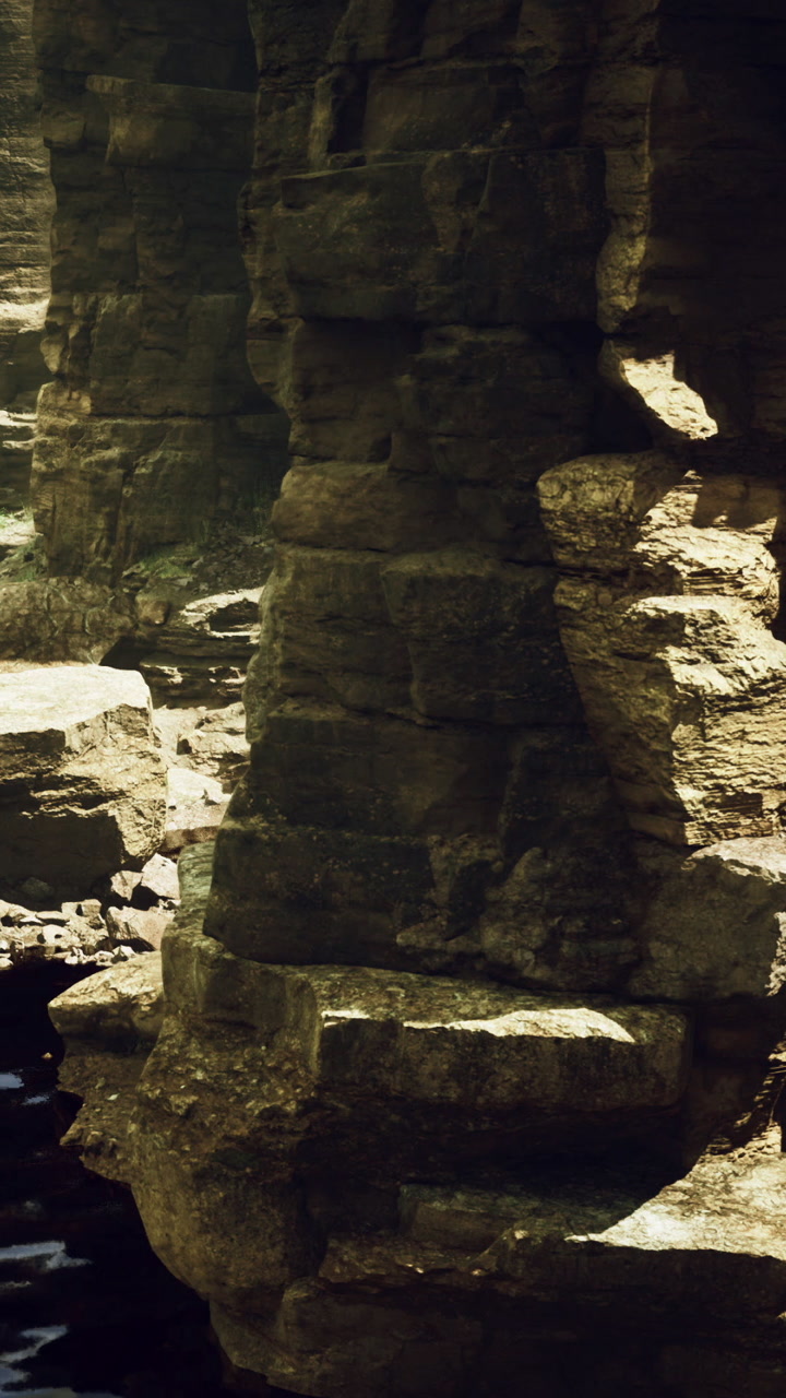 Rock formation along a riverbank with sunlight in a natural setting