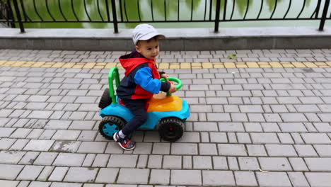 little caucasian boy cheerfully riding his toy car. excited baby on the walk in autumn. top view.