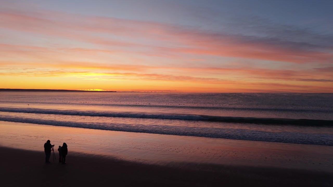 Drone Dolly In of Sunrise Over Atlantic Ocean with People Silhouettes in Puerto Madryn Patagonia