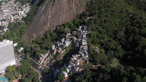 Movimiento-Aéreo-Hacia-Atrás-Que-Muestra-La-Pequeña-Favela-Chacara-De-Río-De-Janeiro-En-Las-Laderas-De-La-Montaña-Dos-Hermanos-Panorámica-Hacia-La-Vista-Más-Amplia-De-La-Ciudad-Con-La-Montaña-Corcovado